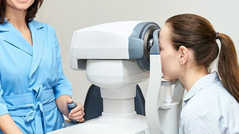 Optician examining woman's eyes with a machine.