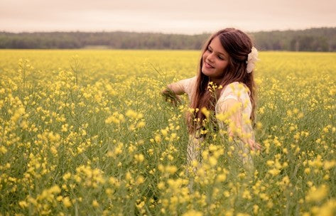 Girl smiling with open arms in field.