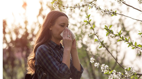 Woman sneezing in spring garden