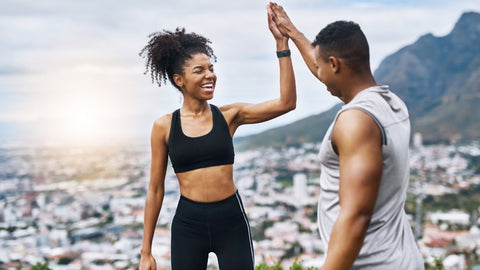 Young couple high fiving while exercising outdoors