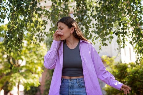 Woman sneezing outdoors.