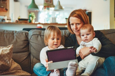 Mom with two kids on the couch using tablet