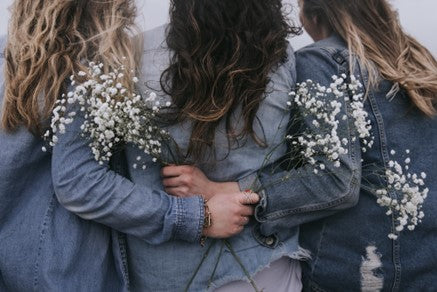 Women hugging and holding flowers.