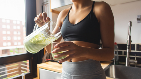 Woman pouring a green smoothie into a glass