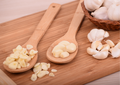 Chopped garlic, in wooden spoons.