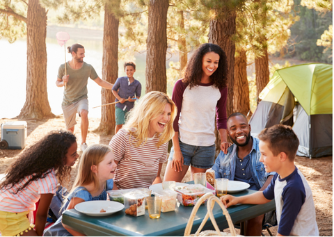 Families sharing a meal outdoors while camping