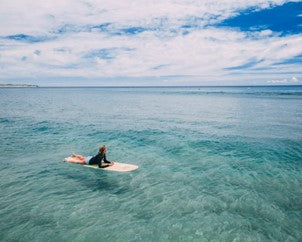 Man on a surfboard in the middle of the sea.