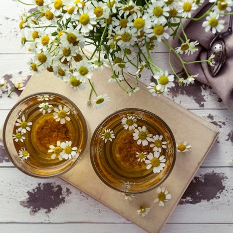 Cup of chamomile tea and chamomile flowers.