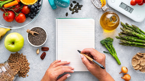 Healthy foods and person writing in notebook