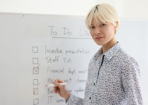 Woman writing a to do list on a whiteboard.