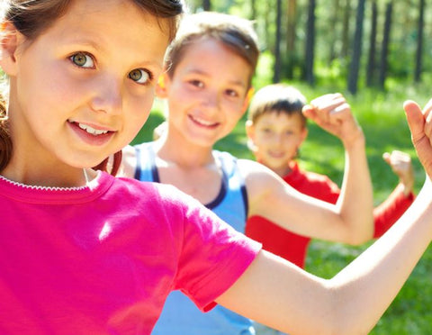 Kids flexing their arms outdoors.