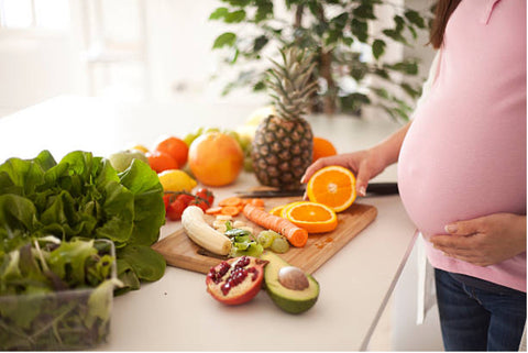 Pregnant woman cutting various fruits