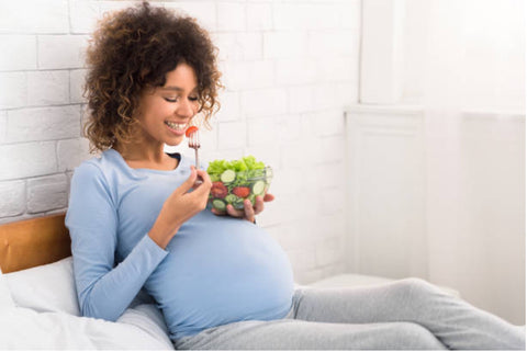 Pregnant woman eating a healthy salad.