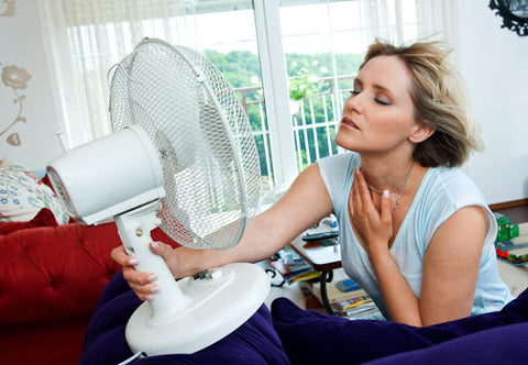 Woman in front of fan to cool down.