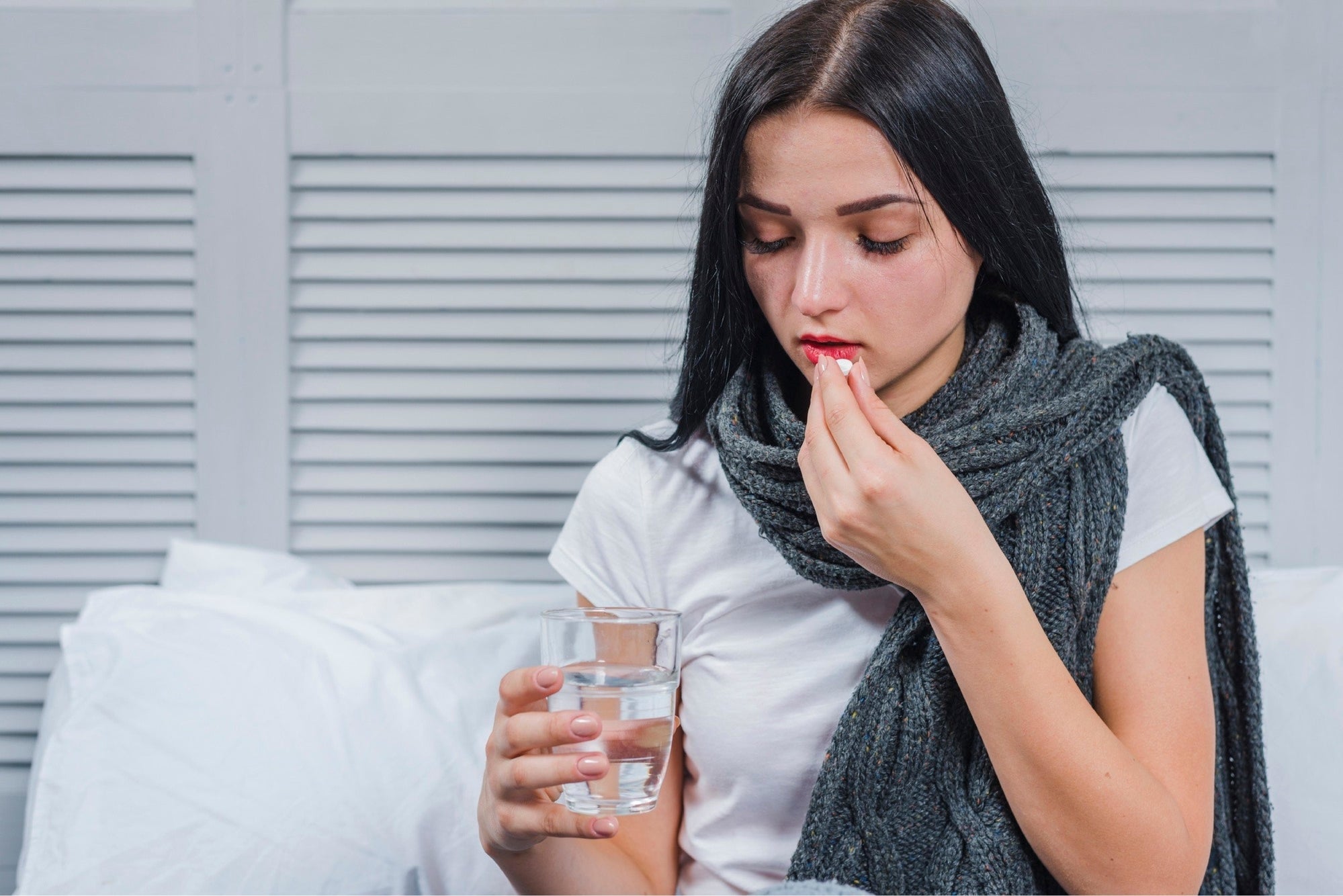 Woman taking pills with water.