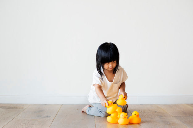 Child playing with yellow ducks.