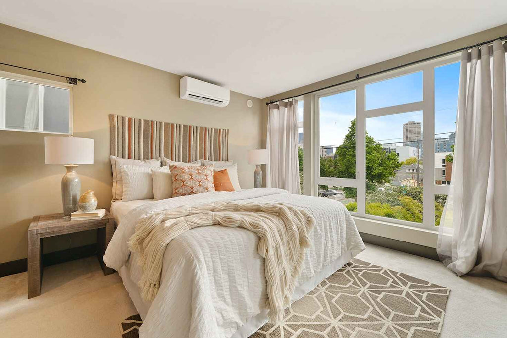 a white and beige bedroom with a lamp and patterned rug