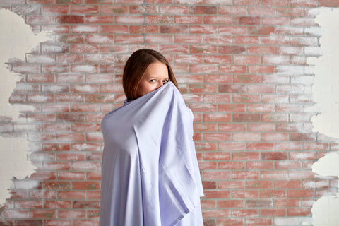 Woman wrapped up in a purple sheet covering most of her face