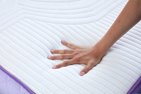 Hand pressing into a mattress