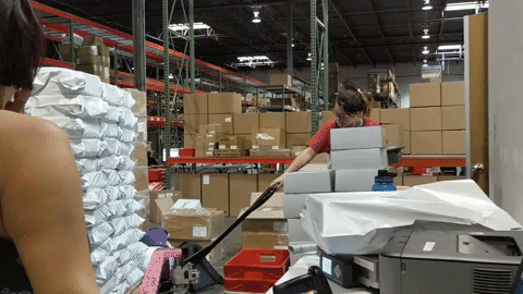 woman pulling a pallet of sheets in a factory