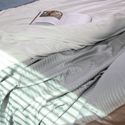 gray stripe sheets on a bed with a white comforter