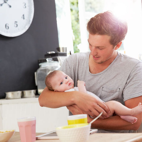 father eating breakfast while holding baby