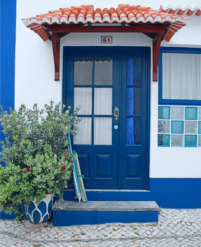 A blue door on a cobblestone street in Ericeira, Portugal