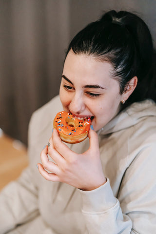 A woman taking a bite of a doughnut
