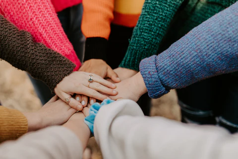 A photo of women's hands coming together in a huddle