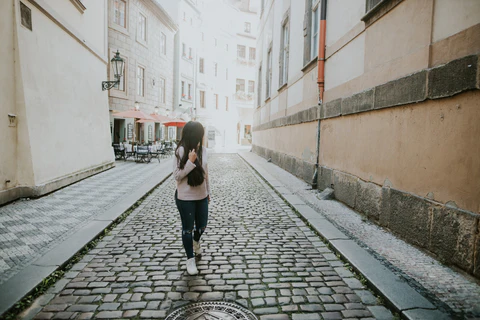 A dark-haired women walks down a cobblestone street in Prague.