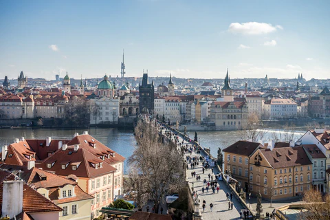 Landscape photo of Prague. A crowd of people walk down the Charles Bridge.