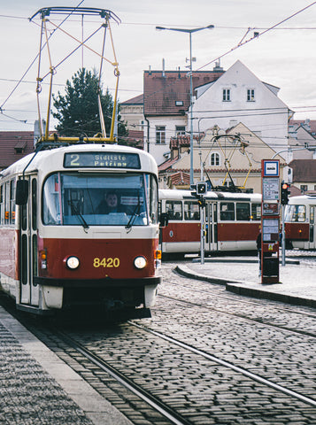 Two red tram cares coming around a street corner in Prague.