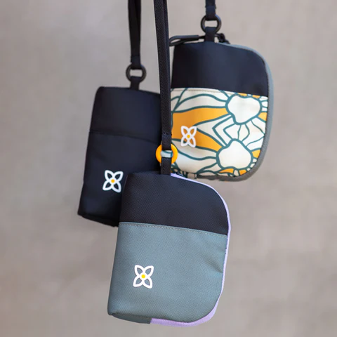 Image of three Sherpani Jolie wristlet pouches dangling into view in Juniper, Fiori and Raven colors.