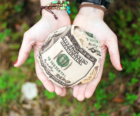 A woman's hands holding a ball of dollar bills