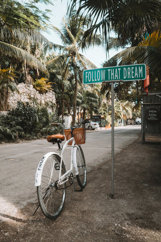 A cruiser bike sitting next to a sign that says "Follow That Dream"