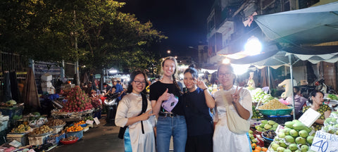 A group of four women standing in a market at nighttime in Ho Chi Minh City, Vietnam