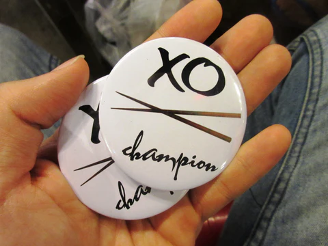 Buttons that say "XO Champion" passed out to game winners on the XO Foodie