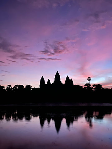 The outline of a temple at sunrise set against a deep purple sky