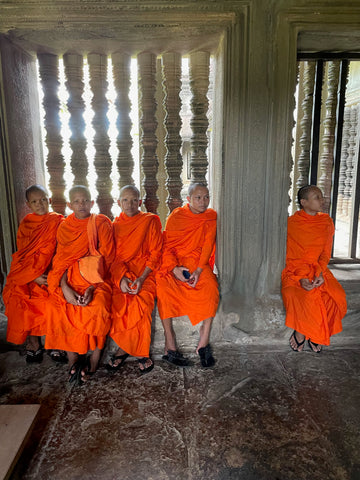 Young monks in orange robes sitting in a line