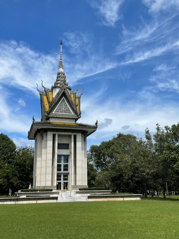 A Cambodian temple in a park with green grass and blue sky