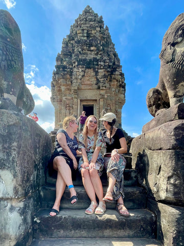 The women sitting side-by-side on the steps of a Cambodian temple