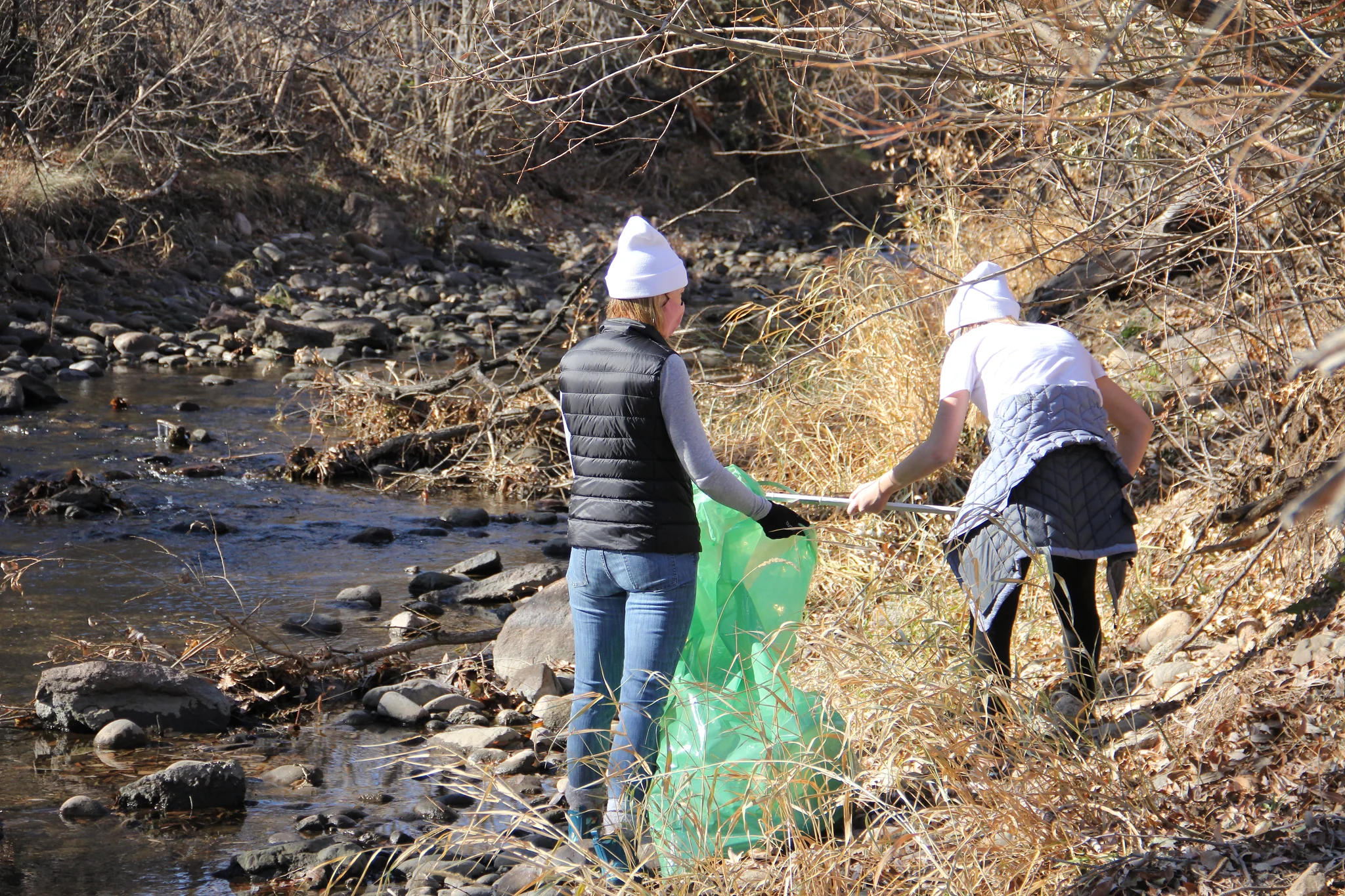 Two people helping each other collect litter