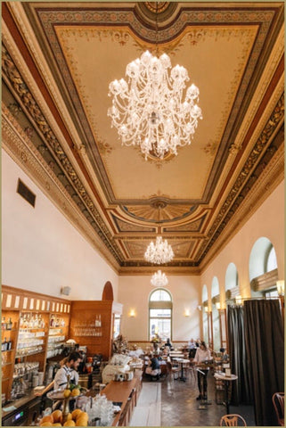 Inside Cafe Savoy with wooden interior and chandeliers.