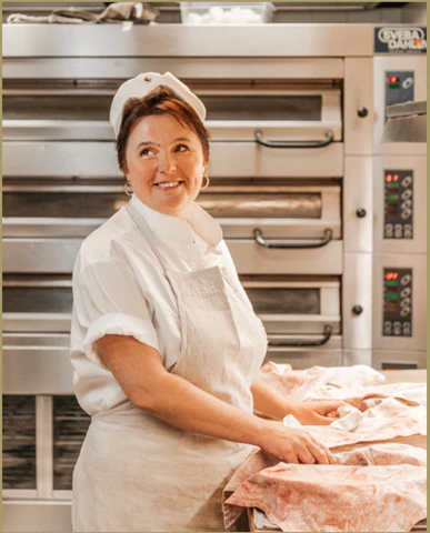 A woman chef Cafe Savoy smiles while working.