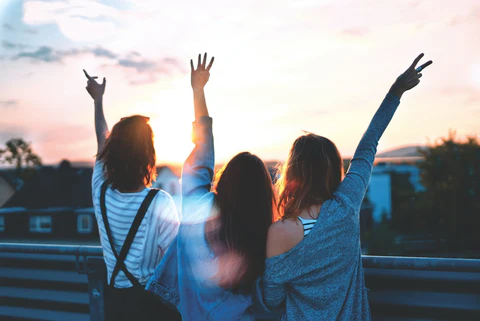 Three women facing away from the camera making various hand gestures