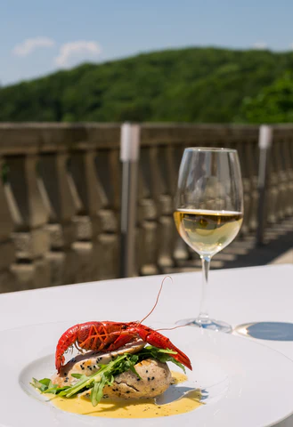 A glass of white wine and seafood dish sit on an outdoor table.