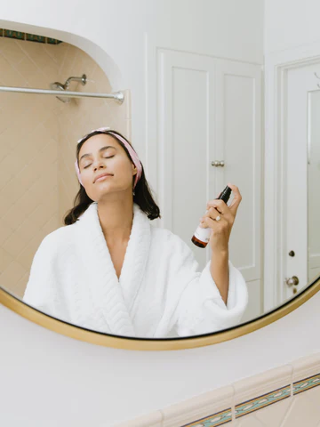 A woman puts on beauty mist in front of a mirror