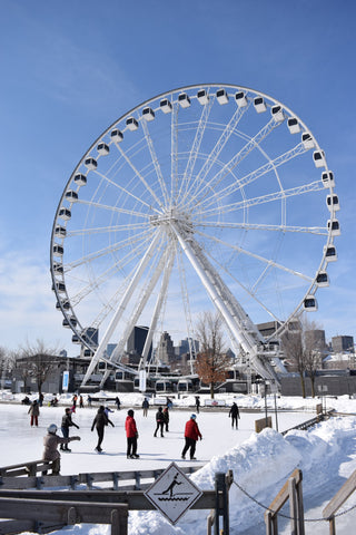 People ice skating outside in front of a large ferris wheel in Montreal, Quebec