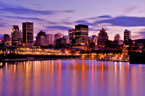 An evening skyline of Montreal over the water with striking purple hues