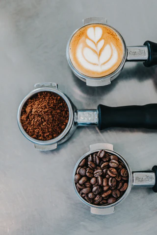 High end coffee beans, ground coffee and latte art sitting in a row